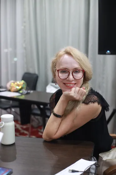 Участница за столом улыбается